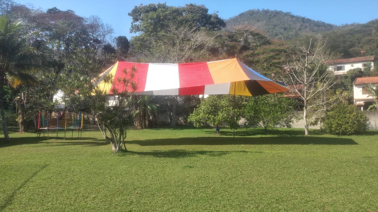Tenda colorida vermelha e branca montada em jardim para festa