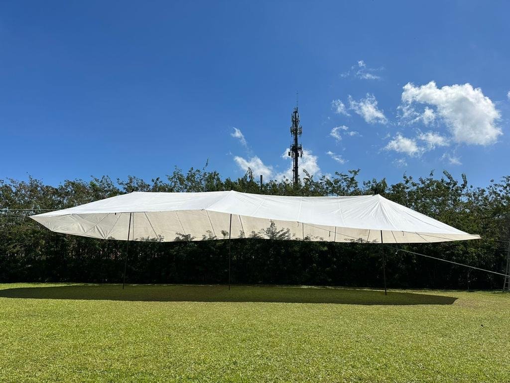 Tenda tensionada branca em gramado com céu azul